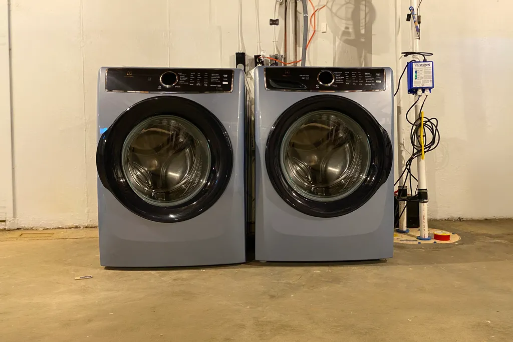Two front-loading washers and dryers in a utility room.
