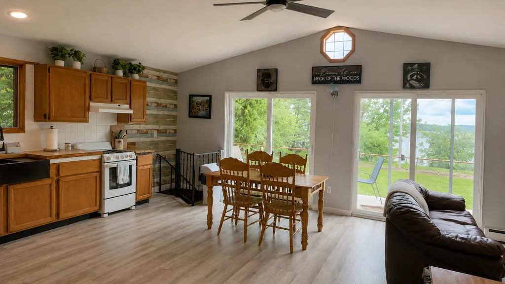 Open kitchen and living area with dining table, couch, and large windows.